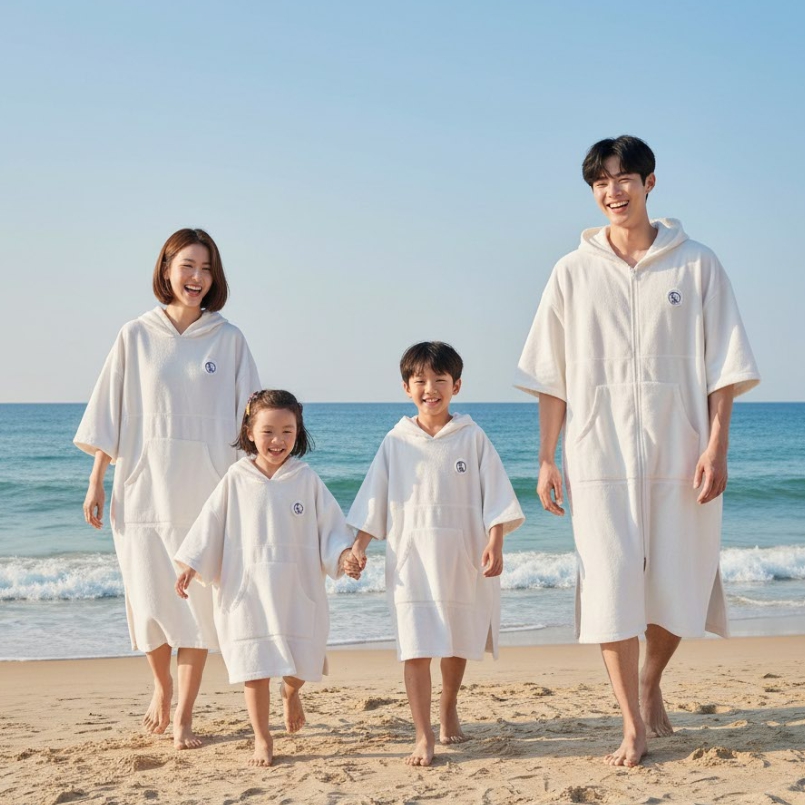 맞소잉 판초타월을 입은 가족이 바닷가를 걷는 모습